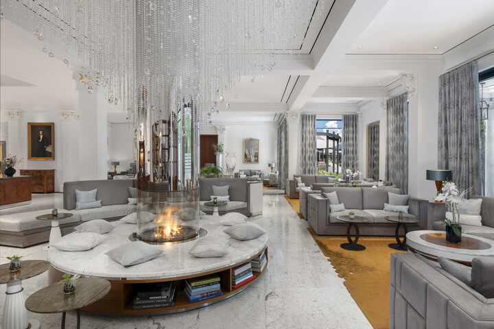 Die Lobby des Grand Resort Bad Ragaz ist zu sehen. Sessel und Sofas stehen um einen Feuerplatz herum. Das Resort ist ein Sternehotel in der Schweiz.