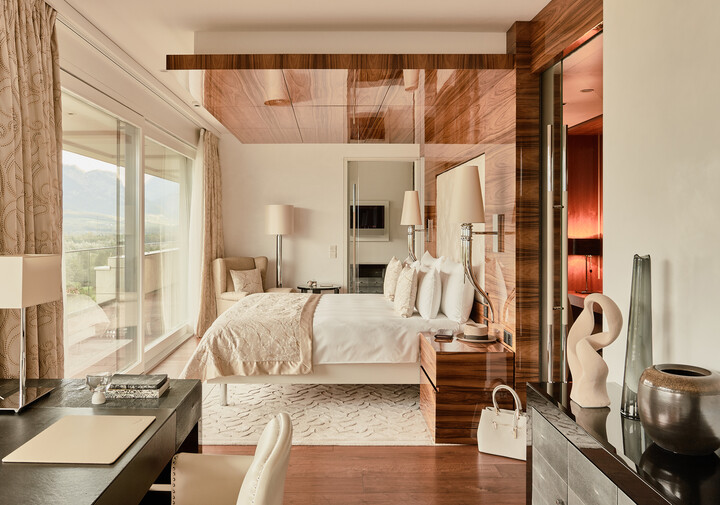 Luxuriöses Schlafzimmer der Penthouse Suite mit grossem Bett, Holzakzenten und eleganter Einrichtung. Raumhohe Fenster bieten einen malerischen Blick auf die Berge und schaffen eine ruhige Atmosphäre.