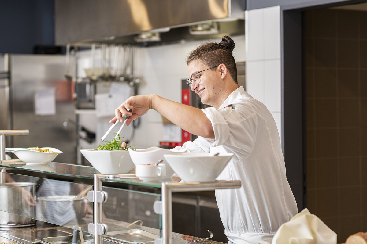Four chefs from the Hotel Grand Resort Bad Ragaz stand around a counter and cut vegetables.