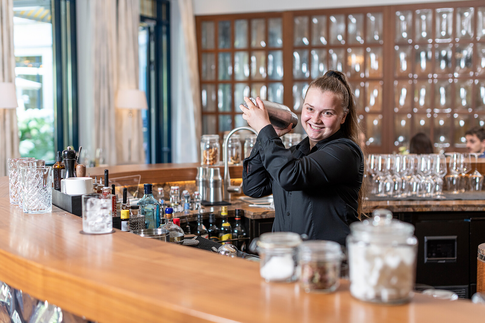 Der Lehrling der Restauration steht an der Bar und mixt ein Getränk. Die Bar befindet sich in dem Hotel Grand Resort Bad Ragaz, einem Sternehotel in der Schweiz.