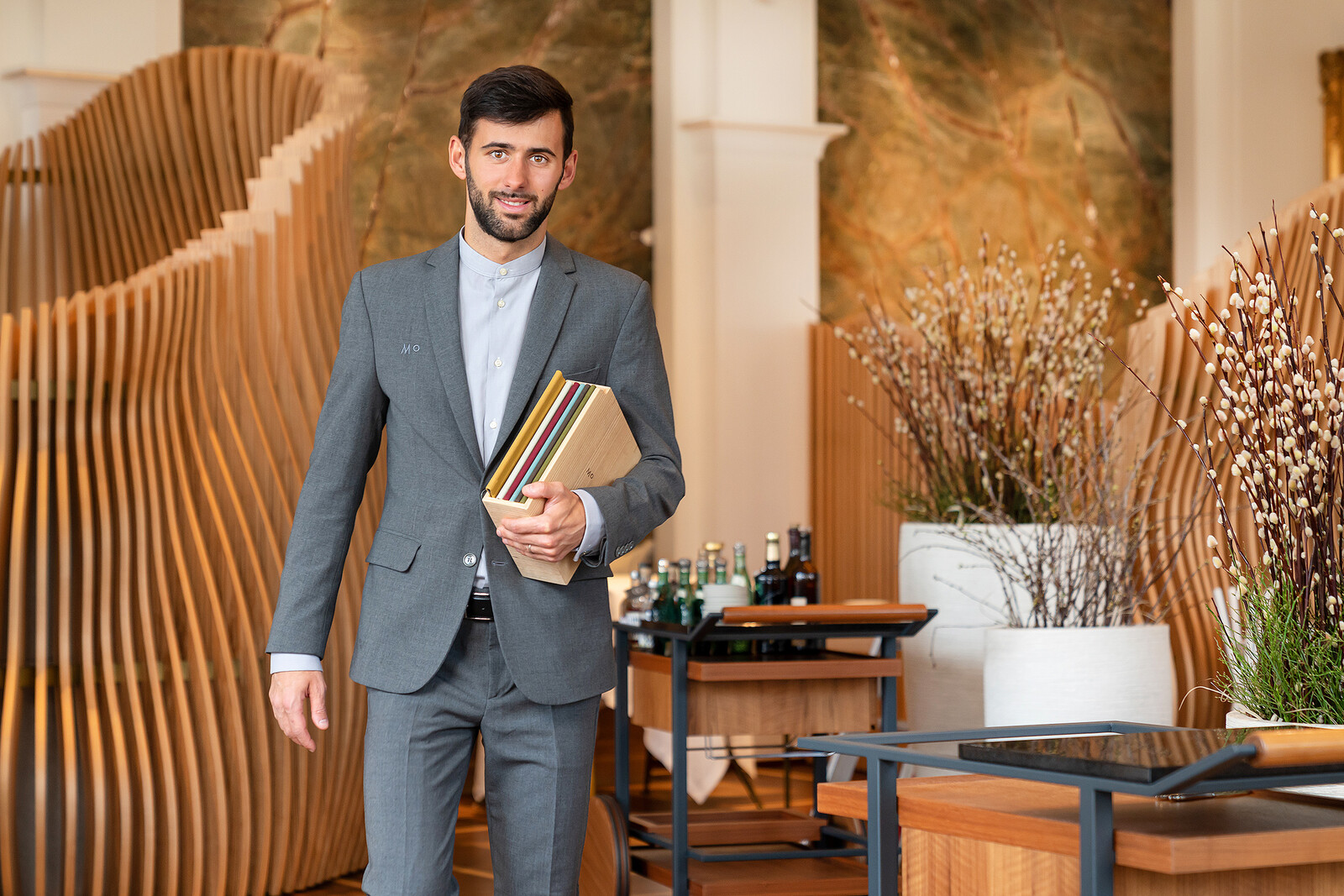 Manuel Masala läuft mit Speisekarten durch das Restaurant Memories. Das Restaurant gehört zum Hotel Grand Resort Bad Ragaz, einem Sternehotel in der Schweiz.