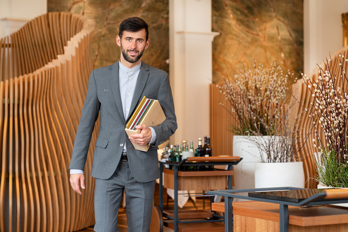 Manuel Masala läuft mit Speisekarten durch das Restaurant Memories. Das Restaurant gehört zum Hotel Grand Resort Bad Ragaz, einem Sternehotel in der Schweiz.