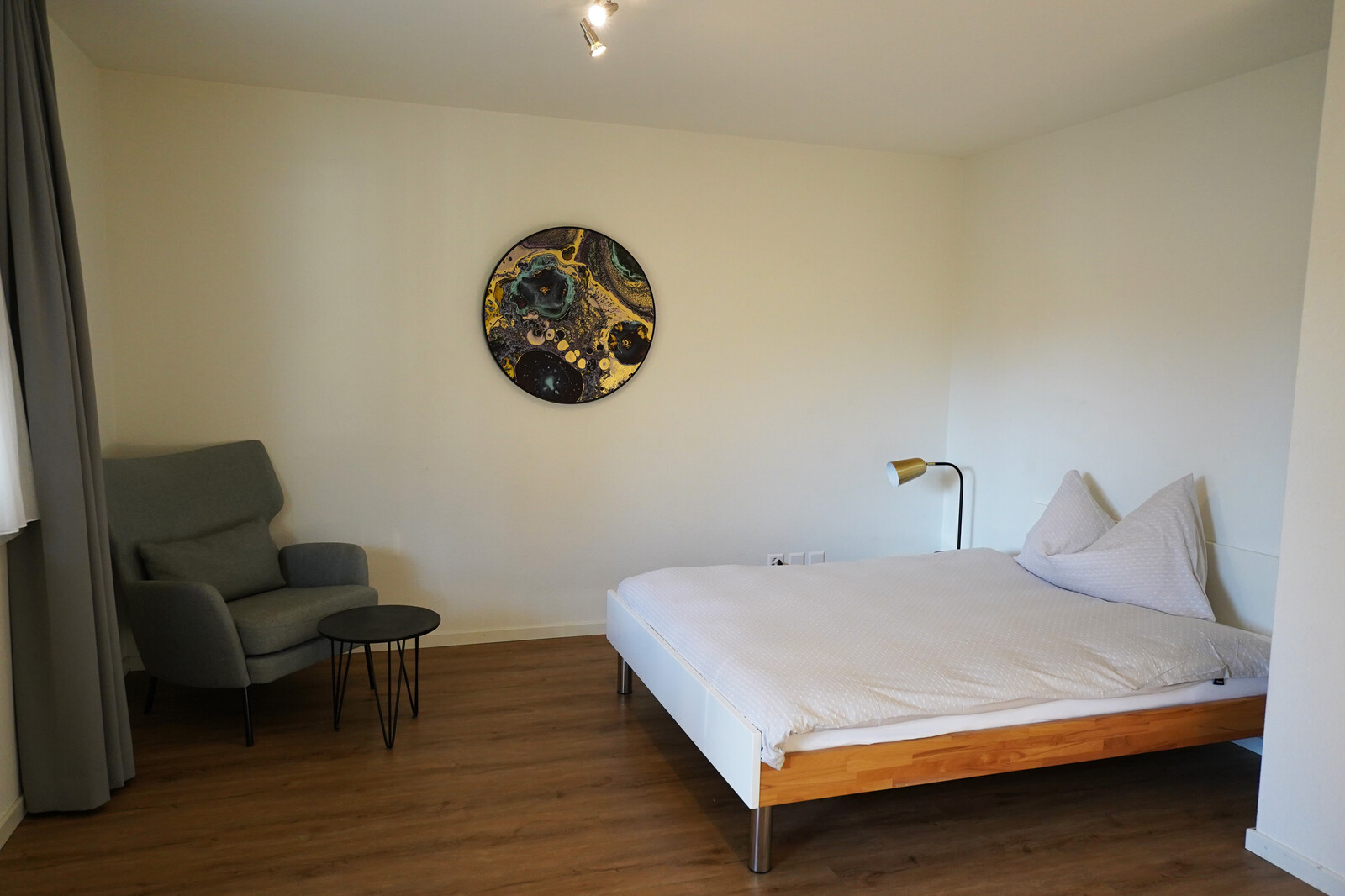 The bed in the staff house on Maienfelderstrasse in Bad Ragaz is in the middle of the room. There is an armchair in the corner. The staff apartments are part of the Grand Resort Bad Ragaz.